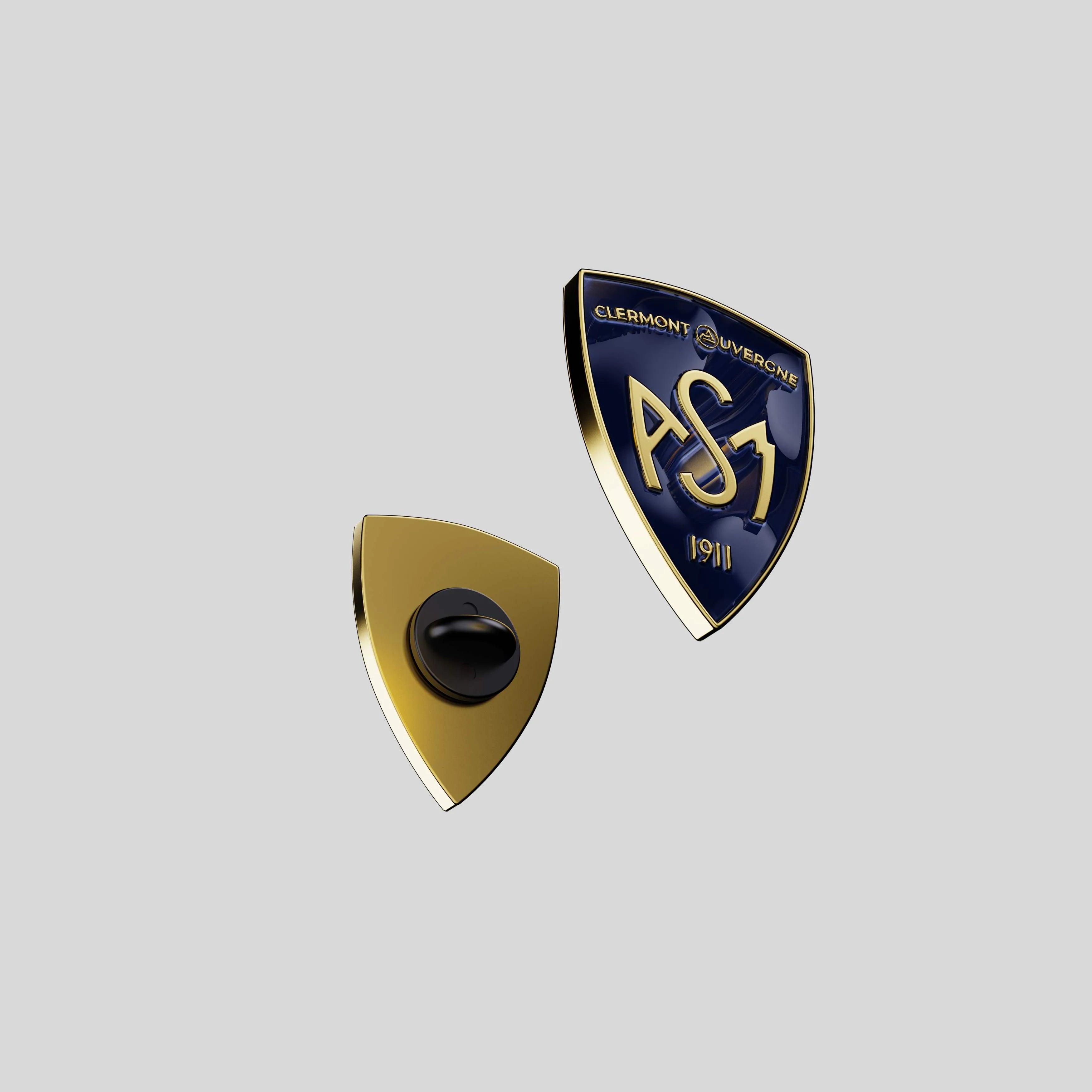 Back view of the ASM shield pin showing gold metal base and black clutch attachment.